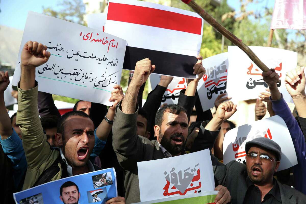 Yemeni expatriates and Iranians chant slogans during a protest against the Saudi-led coalition strikes on Yemen, in front of the Saudi Embassy in Tehran, Iran, Monday, April 13, 2015. The placard at top left is a quote from Iranian supreme leader Ayatollah Ali Khamenei condemning Saudi-led strikes on Yemen. The placard at bottom in Persian reads, "aggression against Yemen." (AP Photo/Ebrahim Noroozi)