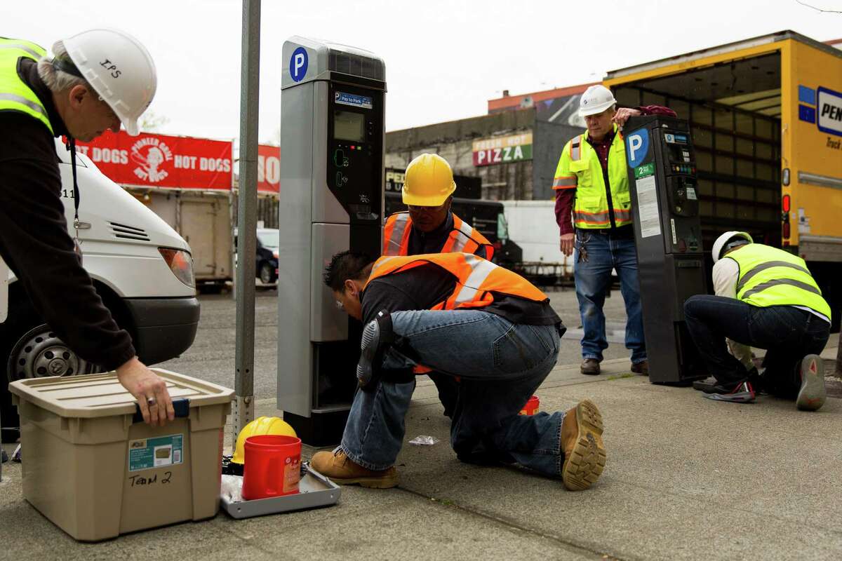 SDOT employees work to swap an old parking station, right, out for one of 2,200 new smart parking pay stations, left, on Monday, April 13, 2015, near CenturyLink Field in Seattle, Washington. The City of Seattle selected the IPS Group to replace or retrofit all of the city?•s on-street parking pay stations by the end of 2016, boasting a higher level of customer service, communications reliability and variable "time of day" parking rates. Credit card transactions will be faster. New credit card readers allow the user to maintain control of their card, so they will no longer get stuck in pay stations.