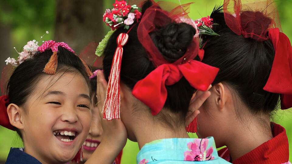 Rokumizu Japanese Dance Academy member Haruna Torikai, 10, smiles at Sara Kimura, 9, as they prepare to perform on stage during the 20th annual Japan Festival in Hermann Park on Sunday, April 14, 2013, in Houston. The family event featured performances of contemporary and traditional Japanese music, martial arts demonstrations, along with authentic Japanese cuisine. ( J. Patric Schneider / For the Chronicle )