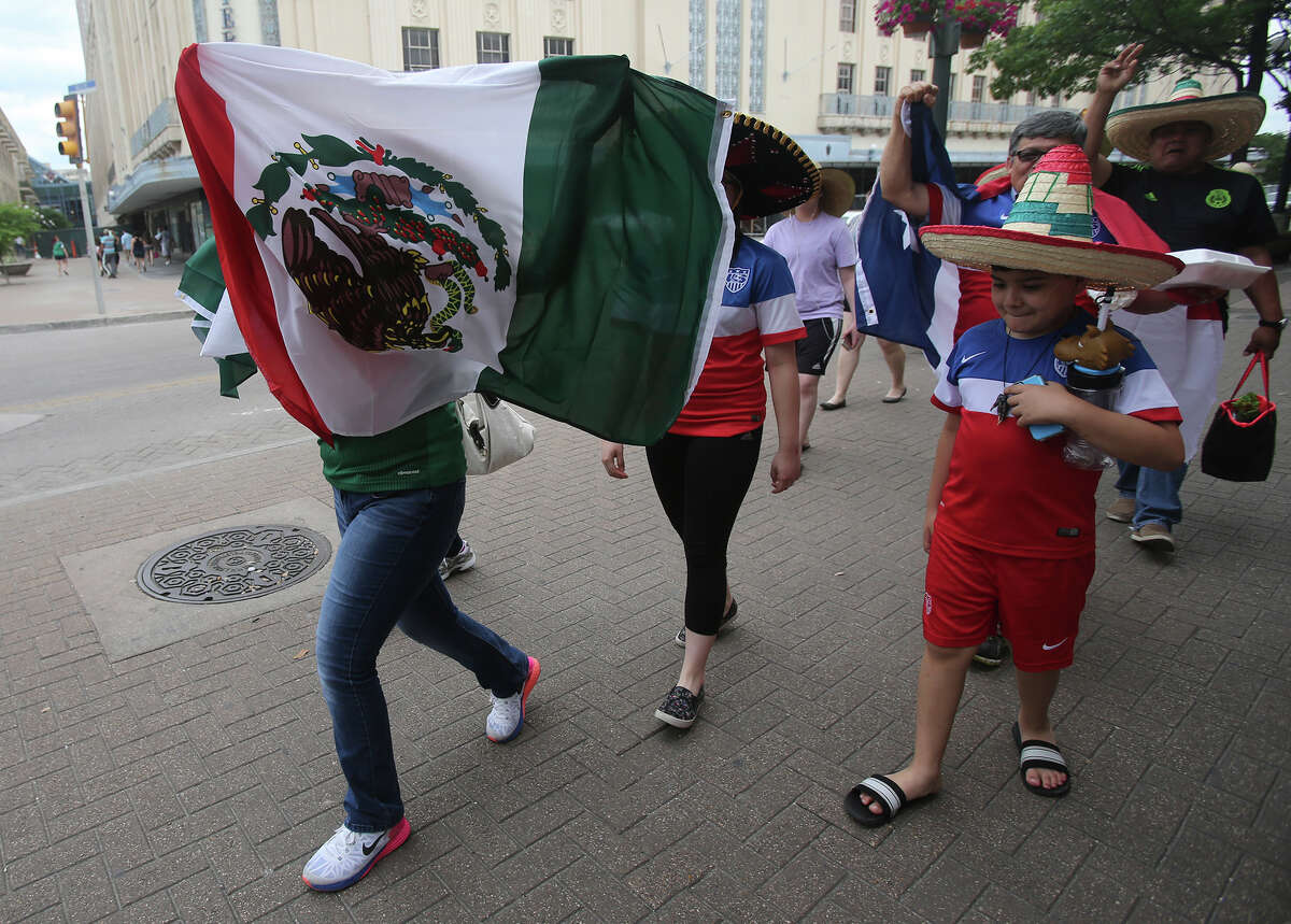 Soccer fans walk in Alamo Plaza Wednesday April 15, 2015 in anticipation of the match between the United States and Mexico's men's national soccer teams to be held at the Alamodome. Leading the charge with the Mexican flag (left) is Arlette Barajas,11, who was with her dad Julio Barajas. The family came from McAllen to see the soccer match.
