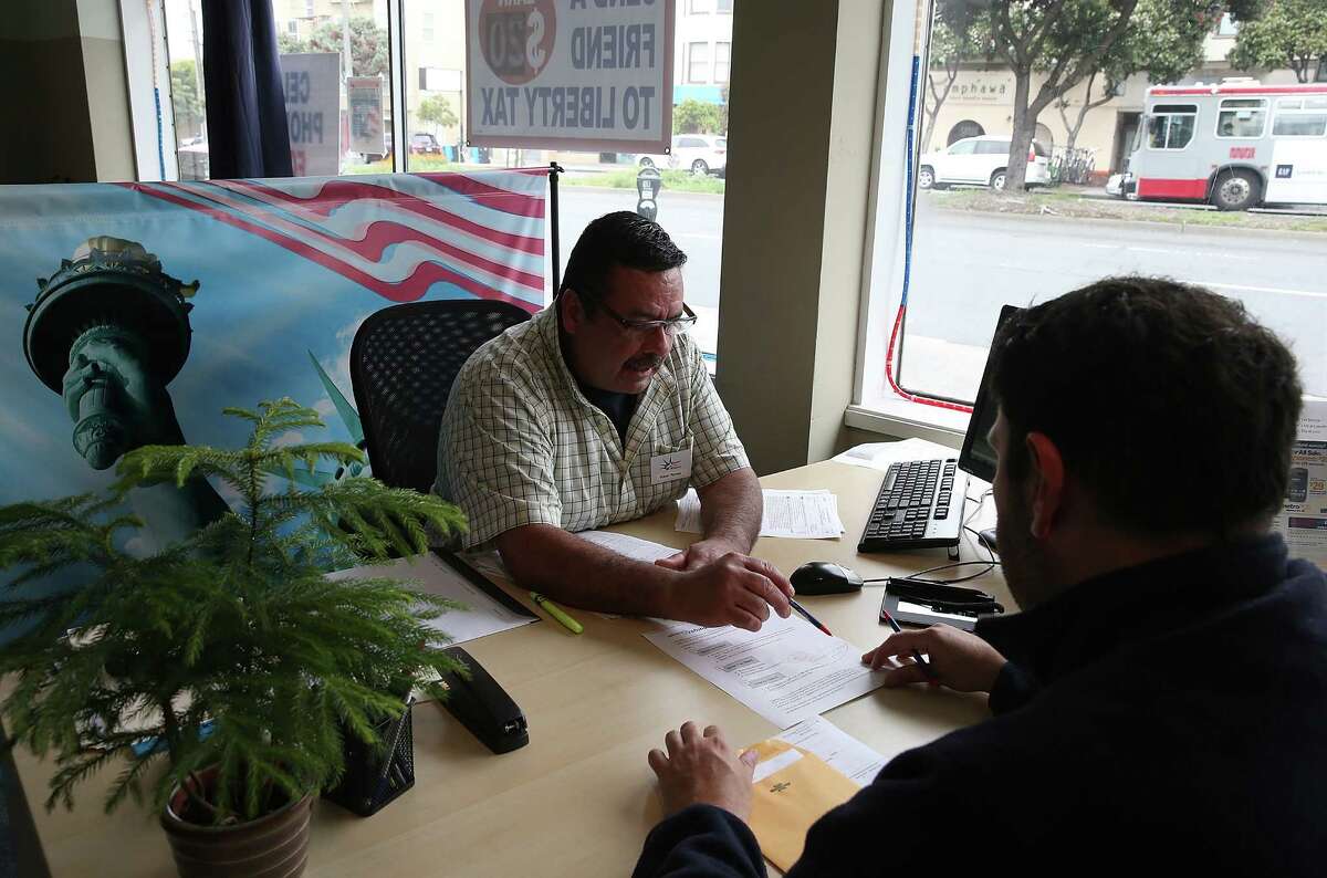 SAN FRANCISCO, CA - APRIL 14: Tax preparer Robert Romero (L) helps a customer prepare his income taxes at Liberty Tax Service on April 14, 2014 in San Francisco, California. Tax preparers are helping last minute tax filers ahead of the April 15th deadline to file state and federal income taxes. The Internal Revenue Service is expecting an estimated 35 million returns in the week leading up to the deadline. (Photo by Justin Sullivan/Getty Images)