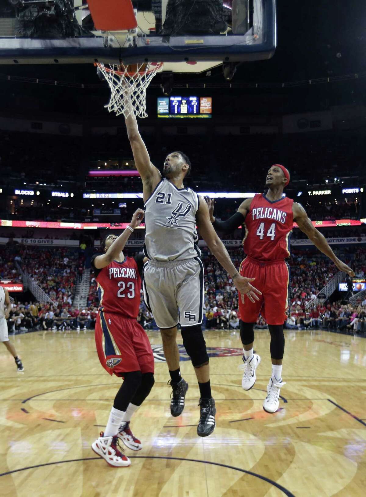 San Antonio Spurs forward Tim Duncan (21) goes to the basket in front of New Orleans Pelicans forward Anthony Davis (23) and forward Dante Cunningham (44) in the first half of an NBA basketball game in New Orleans, Wednesday, April 15, 2015.