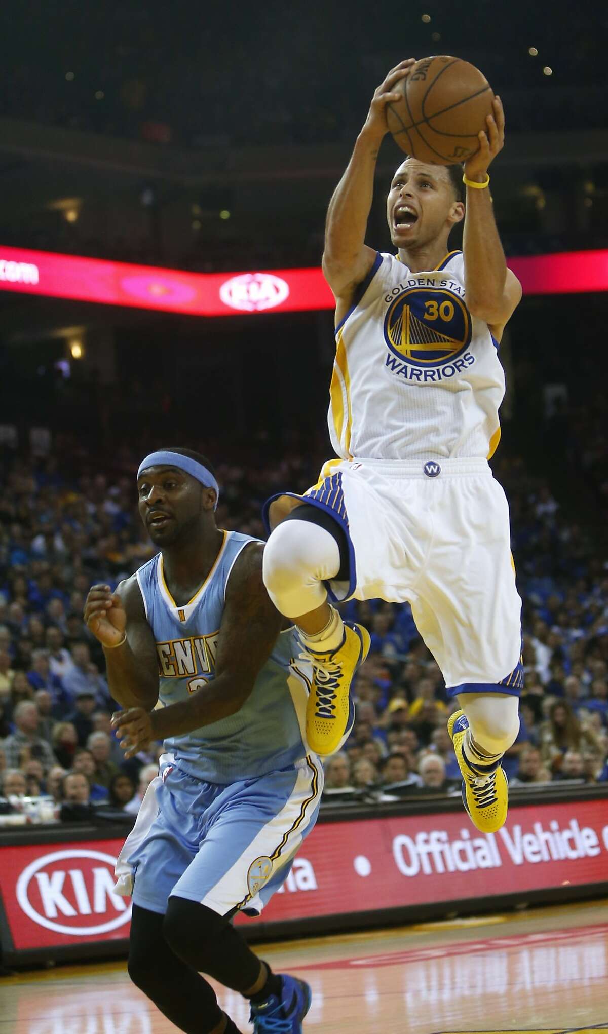 Golden State Warriors' Stephen Curry scores against Denver Nuggets' Ty Lawson during NBA game at Oracle Arena in Oakland, Calif., on Wednesday, April 15, 2015.