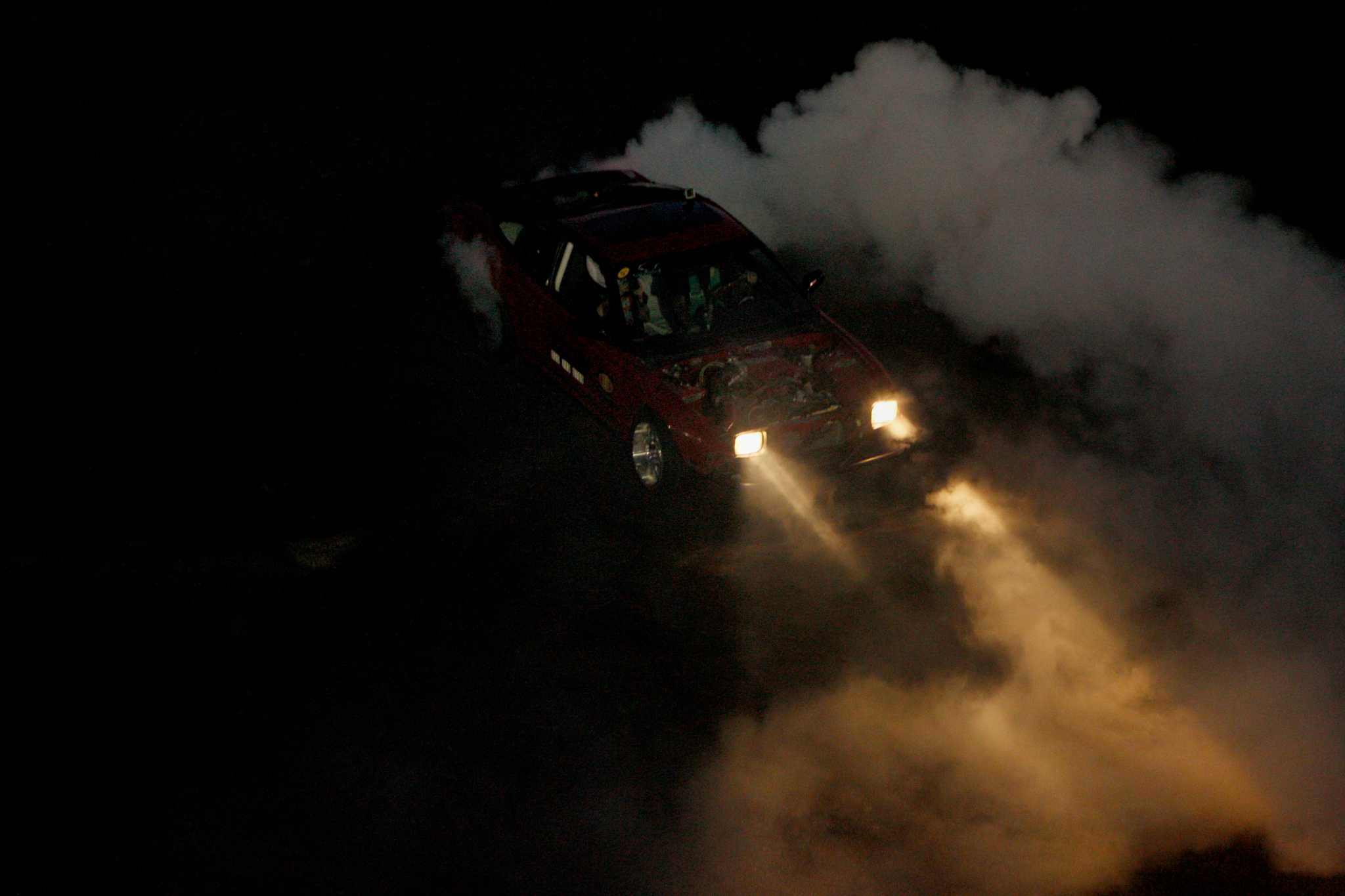 drift car drifting around a tire stack 4k night time