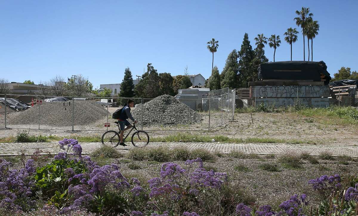 A bicyclist rides past a vacant lot that Michael Johnson hopes to develop across from Lake Merritt in Oakland, Calif. on Thursday, April 16, 2015. Johnson is hoping to build a 24-story residence tower at Lake Merritt Boulevard and East 12th Street but is facing opposition.