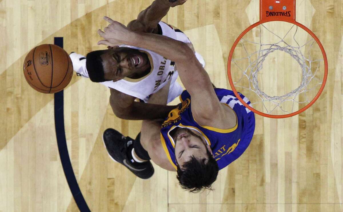 New Orleans Pelicans guard Norris Cole, left, is topped as he drives to the basket against Golden State Warriors center Andrew Bogut in the first half of an NBA basketball game in New Orleans, Tuesday, April 7, 2015. (AP Photo/Gerald Herbert)