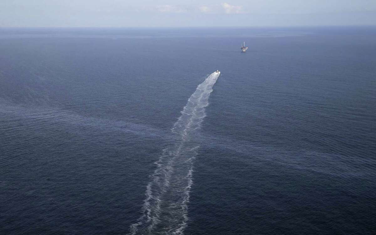 In this March 31, 2015 photo, the wake of a supply vessel heading towards a working platform crosses over an oil sheen drifting from the site of the former Taylor Energy oil rig in the Gulf of Mexico, off the coast of Louisiana. (AP Photo/Gerald Herbert)