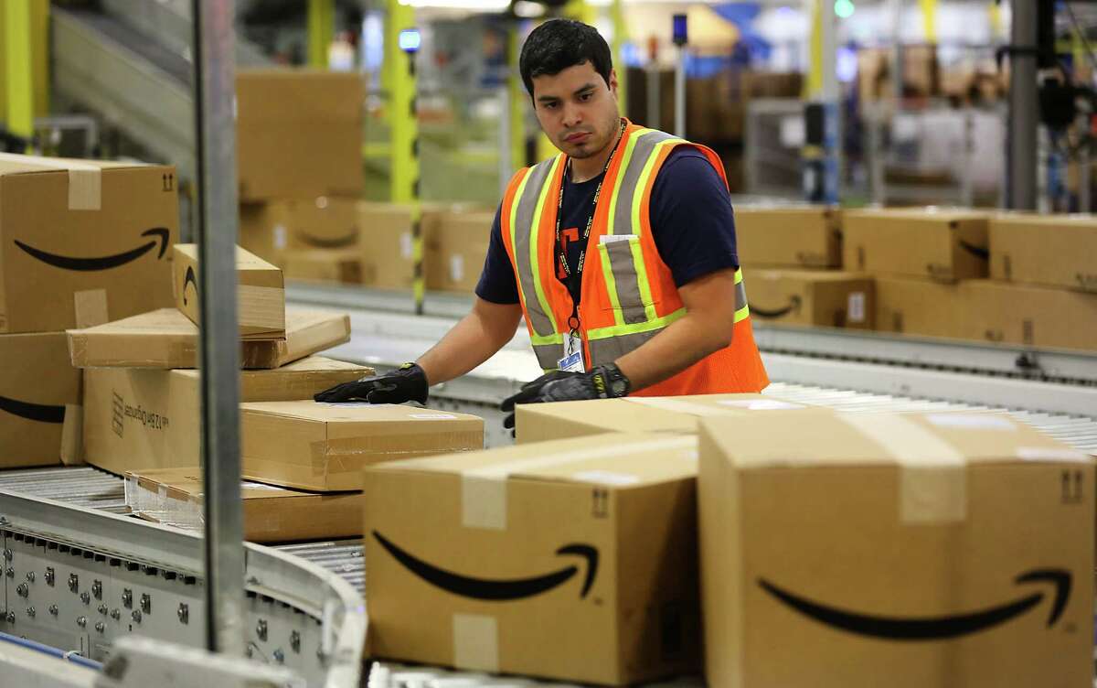 A worker at the Amazon Fullfillment Center in Schertz, TX, inspects packaging on a conveyor belt. Thursday, April 16, 2015.