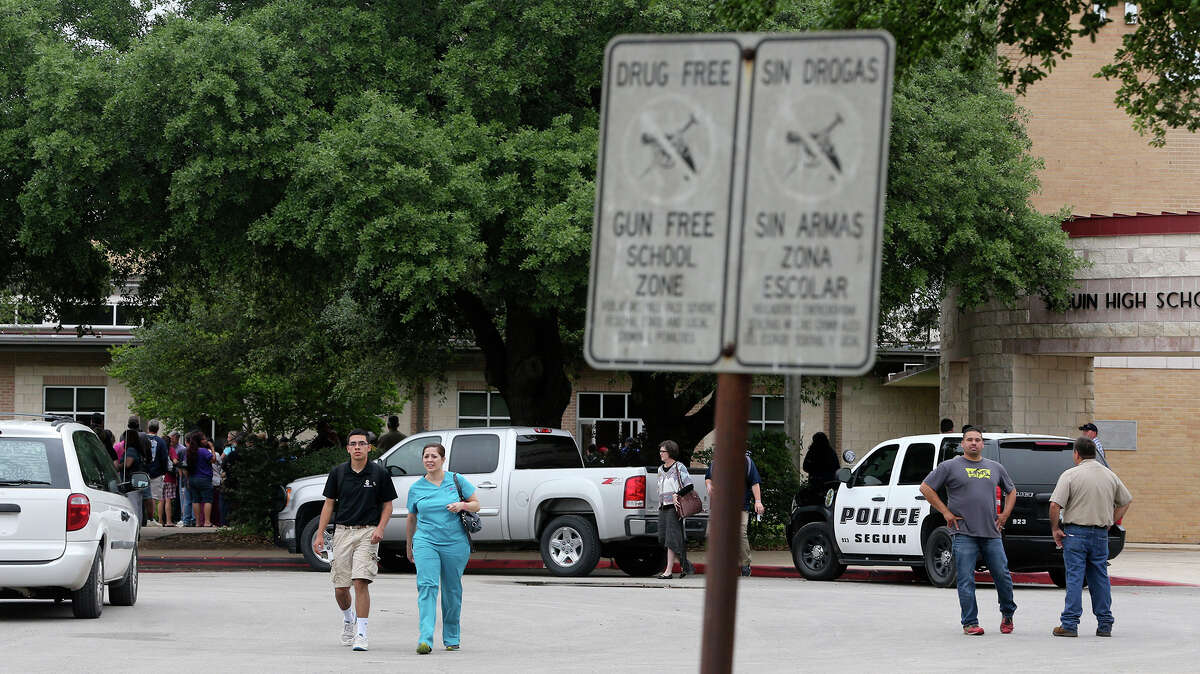 Student Randy Flores (left, foreground),16, leaves Seguin High School Friday April 17, 2015 with his mother April Bustamante (wearing scrubs). There are reports a student may have attempted suicide here today. Parents are lining up to get their children after showing ID.