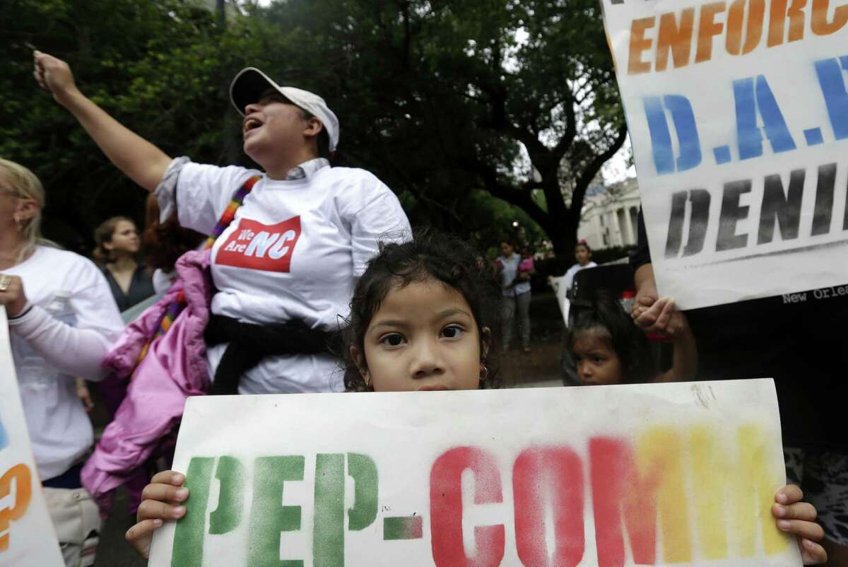 Ashley Ayesdas, 4, holds a sign as her mother, Guatemalan immigrant Maria Arias, behind at left, participates in a rally led by the New Orleans Worker Center for Racial Justice and the Congress of Day Laborers, outside the U.S. Fifth Circuit Court of Appeals in New Orleans, Friday, April 17, 2015. A three-judge panel began hearing arguments whether to lift a temporary hold imposed by a federal judge in Texas on President Barack Obama's executive action seeking to shield millions of immigrants from deportation. (AP Photo/Gerald Herbert)