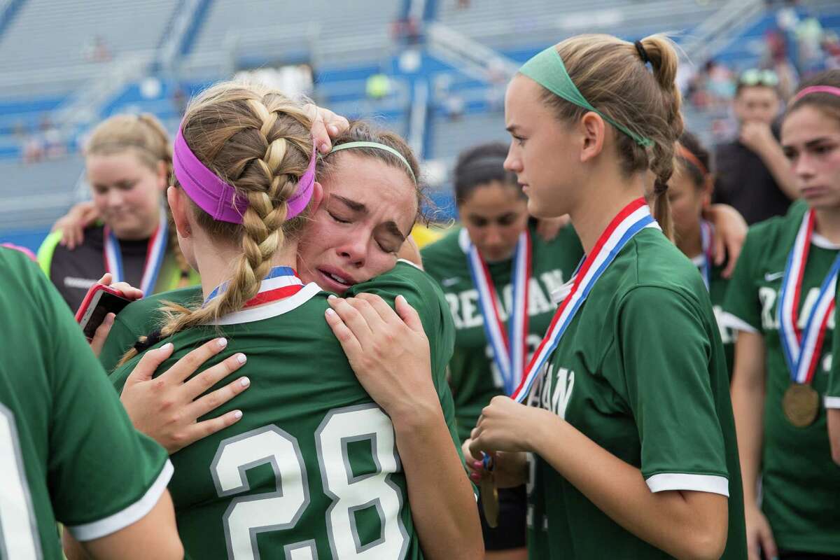 Reagan’s Nicole Galan (center) gets a hug from teammate Taylor Olson after a 1-0 loss to Coppell during the final minute of their 6A girls state soccer semifinal in Georgetown on April 17, 2015.