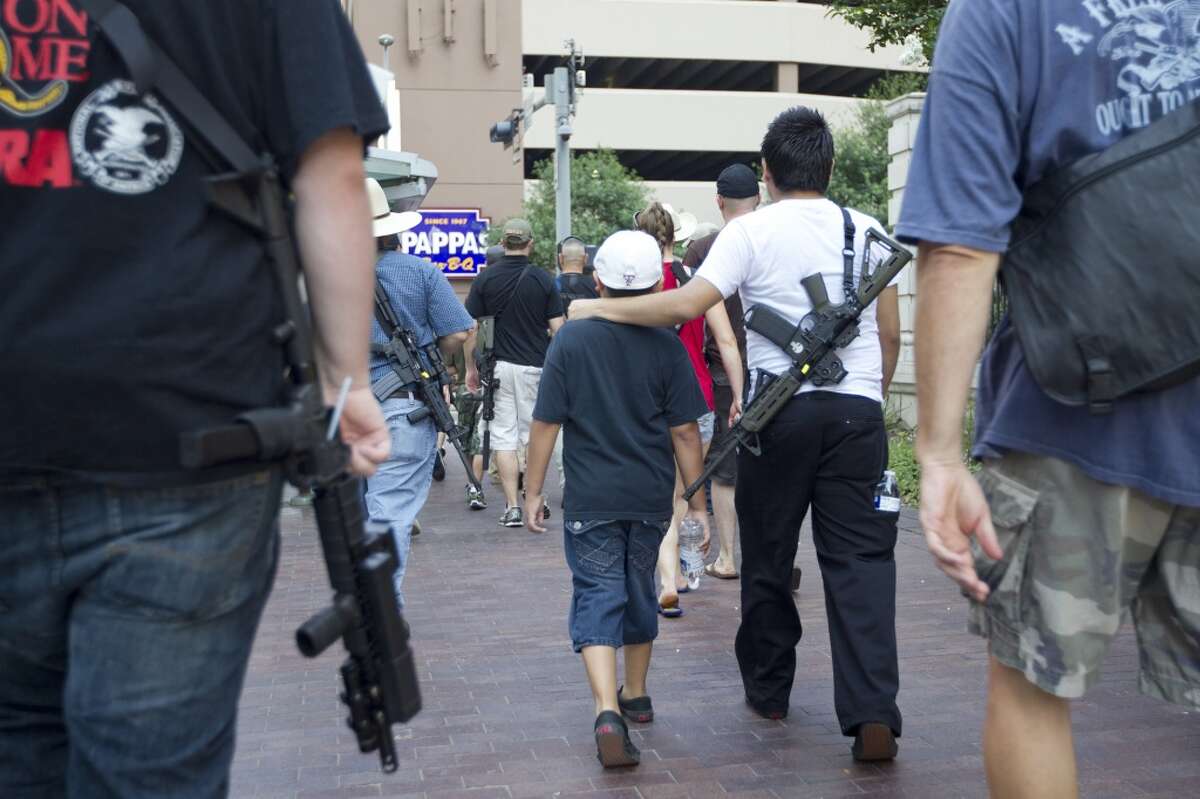 Jr. Velez, 21, puts his arm around his little brother while walking with his AR-15 rifle down Bagby, as they joined a group of more than 20 people with the pro-gun organization, Come and Take it Houston, as part of a rally to educate people about local gun laws Thursday, July 4, 2013, in Houston. "This is a Come and Take it Houston walk to help inform citizens about the gun laws here in Texas," co-organizer Kenneth Lindbloom said. "In Texas there are no restrictions on the open cary of long arms like rifles and shotguns. We want people to realize that in the hands of good people, guns are not dangerous and they don't kill people. When good people have guns it serves as a deterrent to stop crime."( Johnny Hanson / Houston Chronicle )