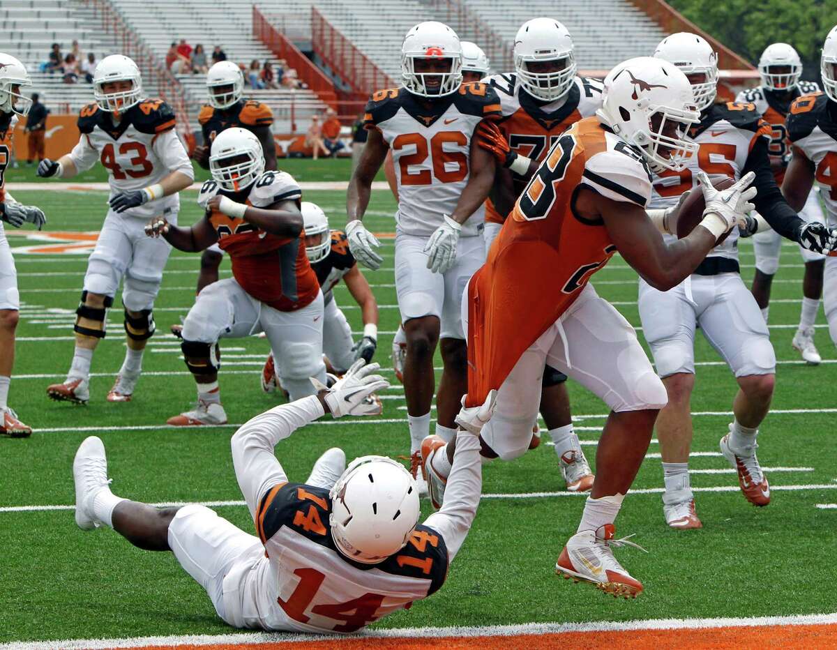 Texas running back Malcolm Brown (28) rushes for a touchdown against Chevoski Collins (14) during the first half of the Orange and White spring game on April 19, 2014, in Austin.