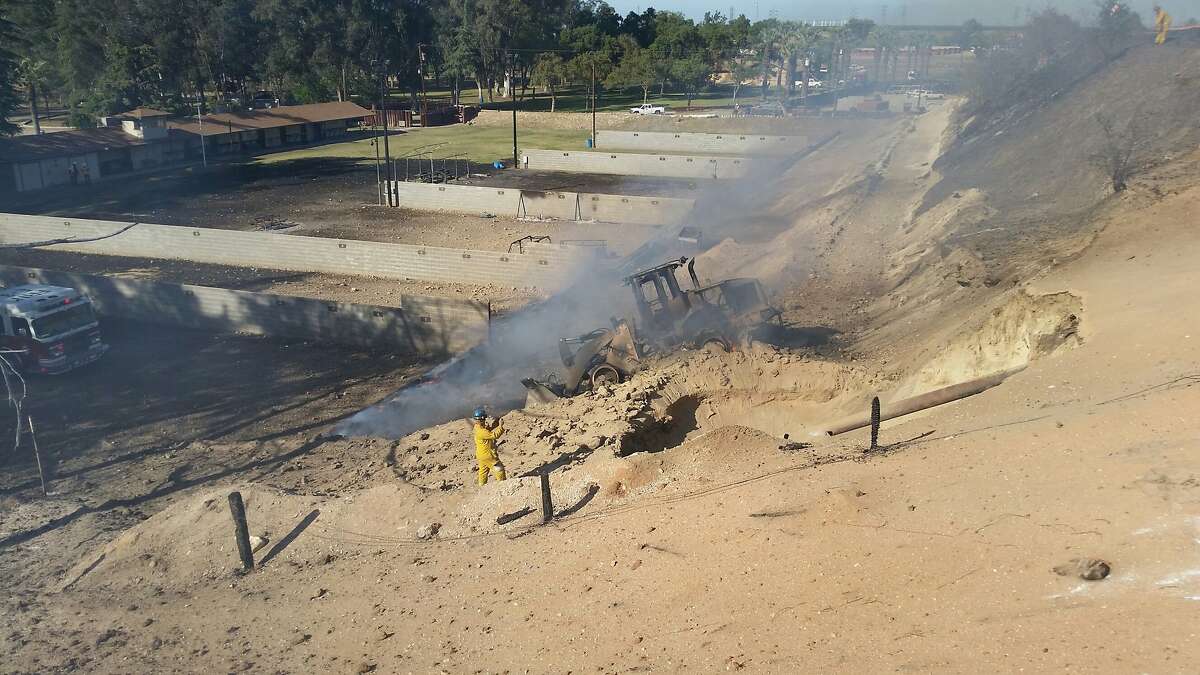Handout photo dated April 17, 2015 of the blast site at Fresno County Sheriffs firing range at 7633 North Weber Ave. PG&E officials, who provided the photo, say it shows a sign (left, center) warning of the presence of an underground natural gas line. At the center of the photo is the burned out front-end loader that triggered the explosion. At right is an exposed part of the gas pipeline.