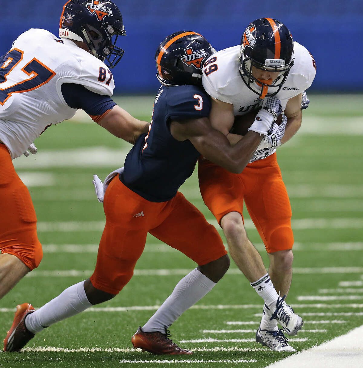 UTSA White Team's Miles Lerch is hit by UTSA Blue Team's Stanley Dye Jr. as UTSA White Team's Trevor Stevens moves in on the play during their Football Fiesta Spring Game held Saturday April 18, 2015 at the Alamodome. UTSA White Team won 57-42.