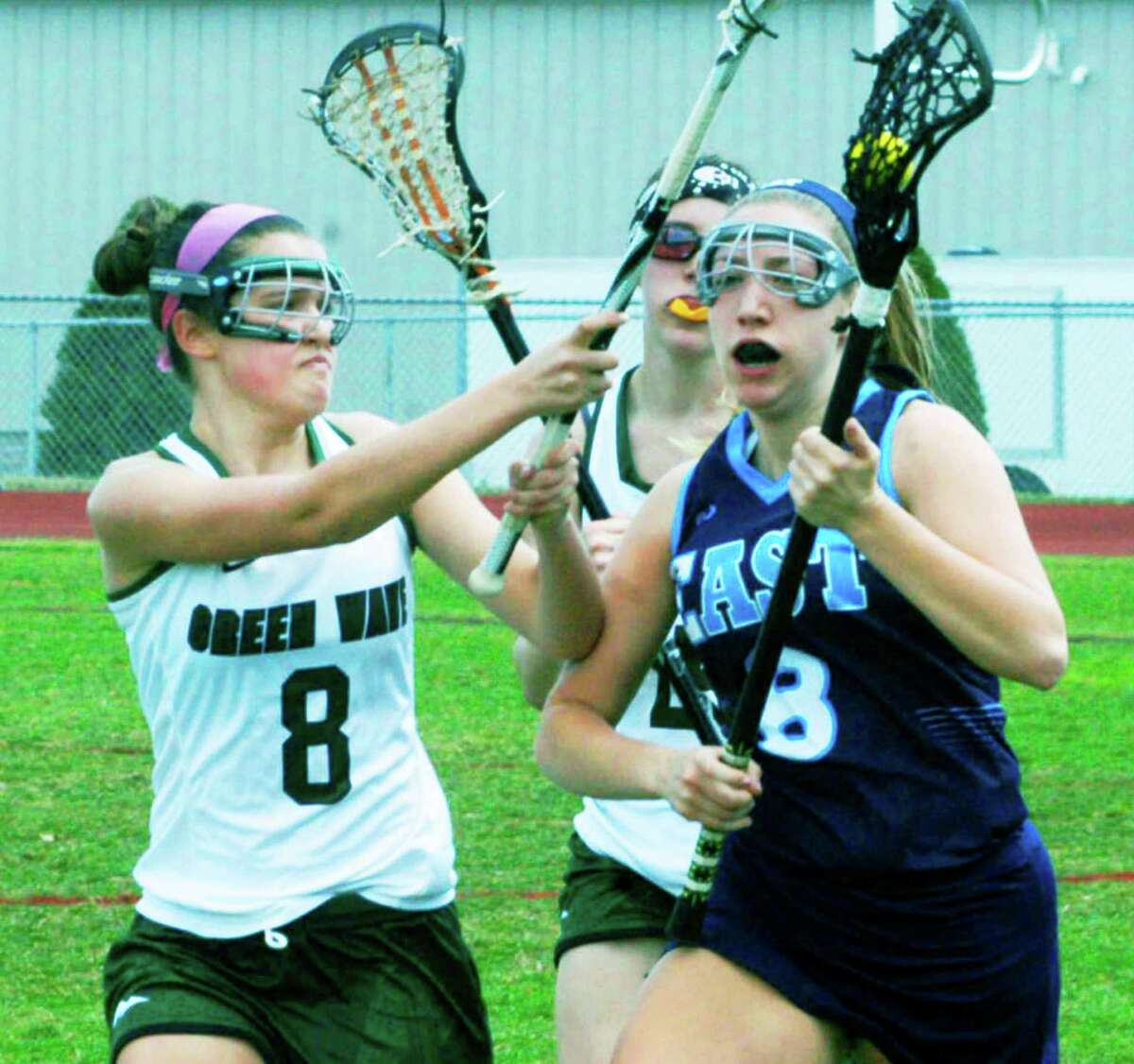 The Green Wave's Autumn Faitak (8) and Natalie Capriglione challenge a rival player for possession during New Milford High School girls' lacrosse's victory over East Catholic, April 18, 2015 at NMHS.
