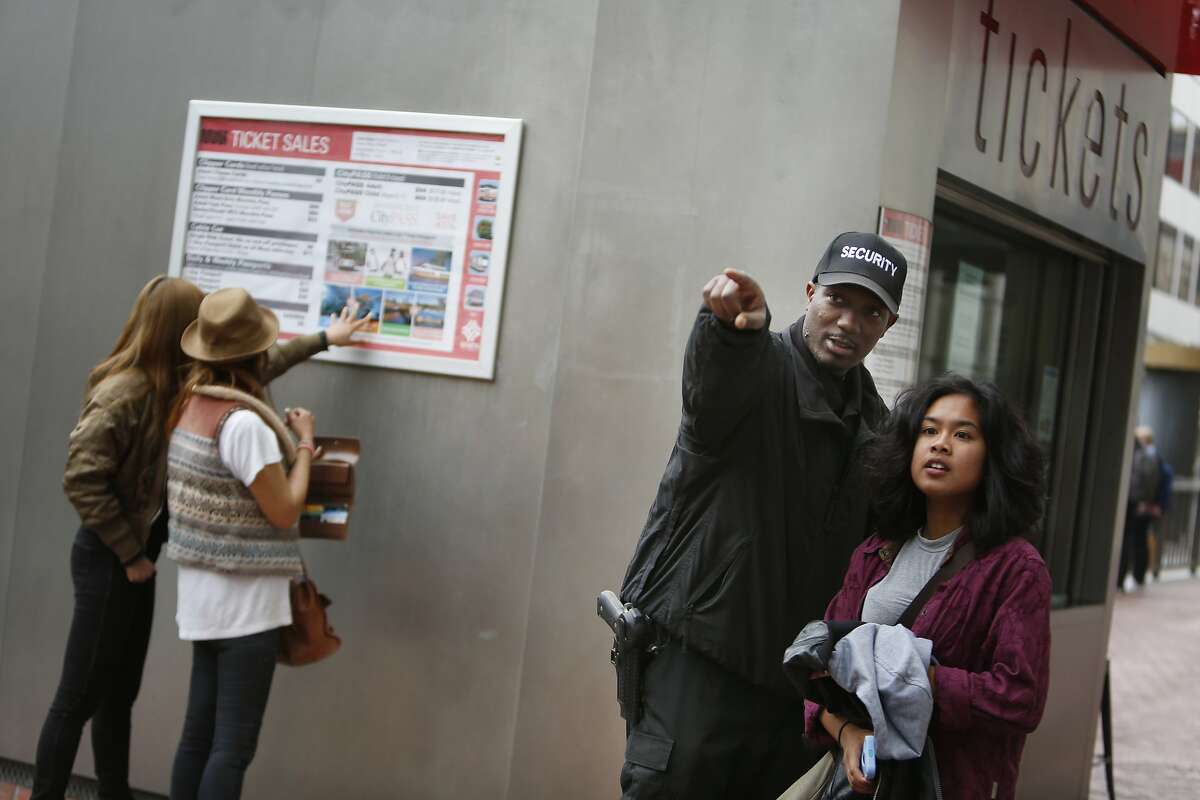 Kasayle Howard (second from right), armed security guard with Cypress Security, helps a passerby with directions while working at the cable car fare kiosk on Powell and Market Streets on Monday, April 20, 2015 in San Francisco, Calif.