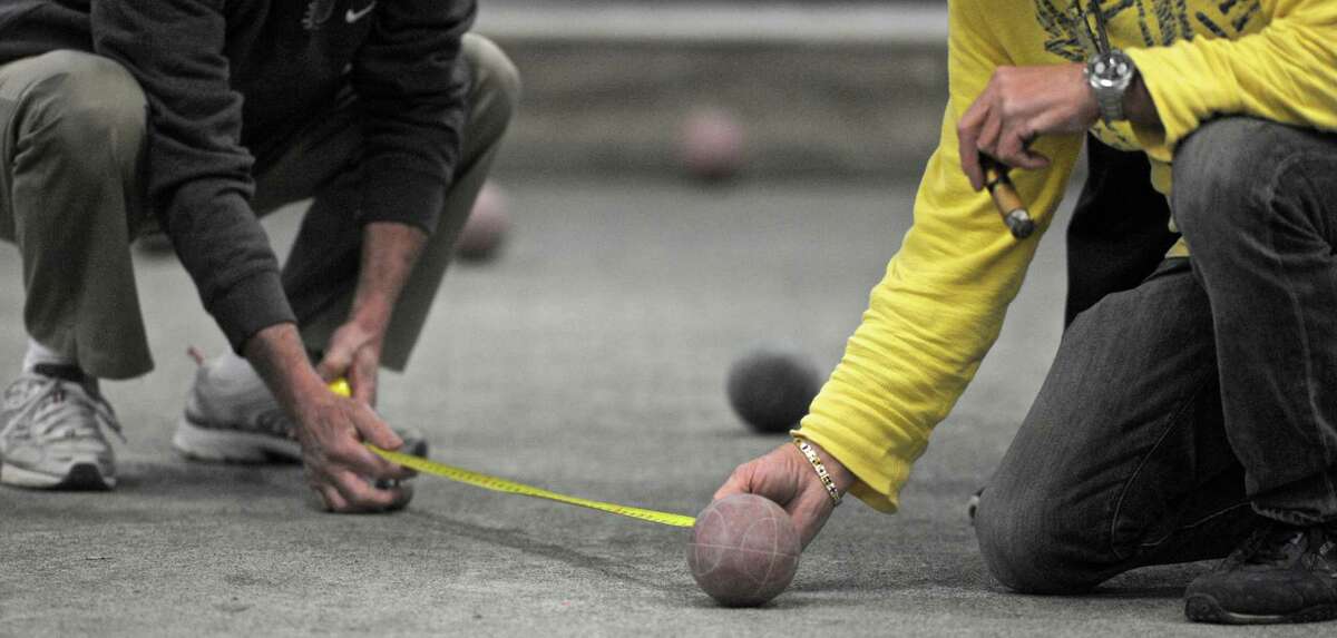 Players measure the distance from the pallino, small ball, to a larger ball during a bocce tournament at the Amerigo Vespucci Lodge #160 in Danbury, Conn, on Tuesday night, April 14, 2015. The distance from the small ball determines which team will bowl next.
