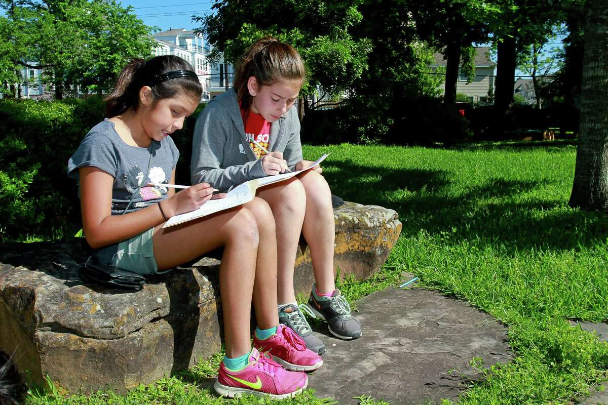 Aurora Mindiola, left, and Lara Manega, both 11, work outdoors on a math problem as part of an "alternative education" event sponsored by ﻿Community Voices for Public Education. ﻿