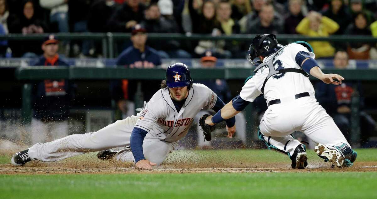 The Astros' Jake Marisnick, left, slides past Mariners catcher Mike Zunino on a third-inning play on which Marisnick was originally called out. The call was changed after a review.