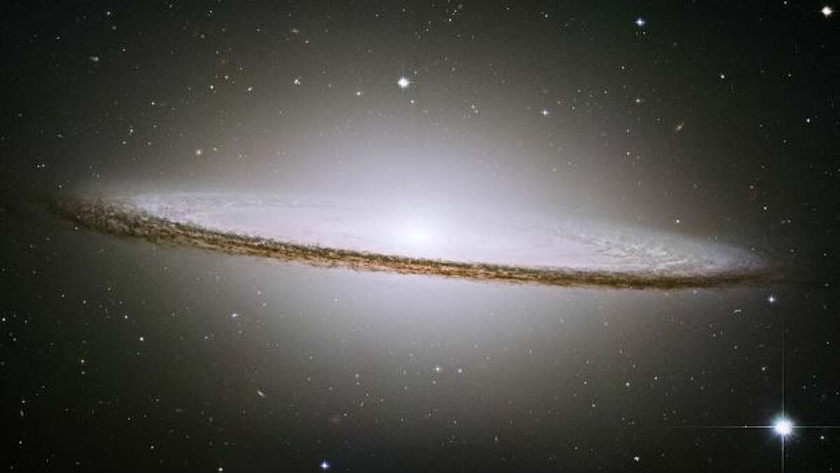 NASA caption: NASA's Hubble Space Telescope has trained its razor-sharp eye on one of the universe's most stately and photogenic galaxies, the Sombrero galaxy, Messier 104 (M104). The galaxy's hallmark is a brilliant white, bulbous core encircled by the thick dust lanes comprising the spiral structure of the galaxy. As seen from Earth, the galaxy is tilted nearly edge-on. We view it from just six degrees north of its equatorial plane. This brilliant galaxy was named the Sombrero because of its resemblance to the broad rim and high-topped Mexican hat. At a relatively bright magnitude of +8, M104 is just beyond the limit of naked-eye visibility and is easily seen through small telescopes. The Sombrero lies at the southern edge of the rich Virgo cluster of galaxies and is one of the most massive objects in that group, equivalent to 800 billion suns. The galaxy is 50,000 light-years across and is located 28 million light-years from Earth. Hubble easily resolves M104's rich system of globular clusters, estimated to be nearly 2,000 in number - 10 times as many as orbit our Milky Way galaxy. The ages of the clusters are similar to the clusters in the Milky Way, ranging from 10-13 billion years old. Embedded in the bright core of M104 is a smaller disk, which is tilted relative to the large disk. X-ray emission suggests that there is material falling into the compact core, where a 1-billion-solar-mass black hole resides. In the 19th century, some astronomers speculated that M104 was simply an edge-on disk of luminous gas surrounding a young star, which is prototypical of the genesis of our solar system. But in 1912, astronomer V. M. Slipher discovered that the hat-like object appeared to be rushing away from us at 700 miles per second. This enormous velocity offered some of the earliest clues that the Sombrero was really...