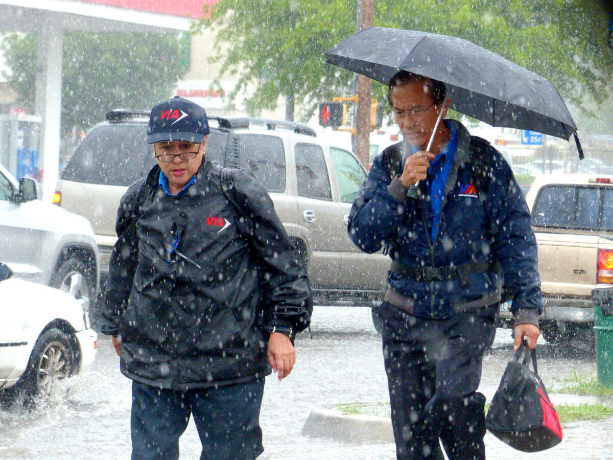 People walk along San Pedro in San Antonio as rain falls on Tuesday afternoon, April 22, 2015.