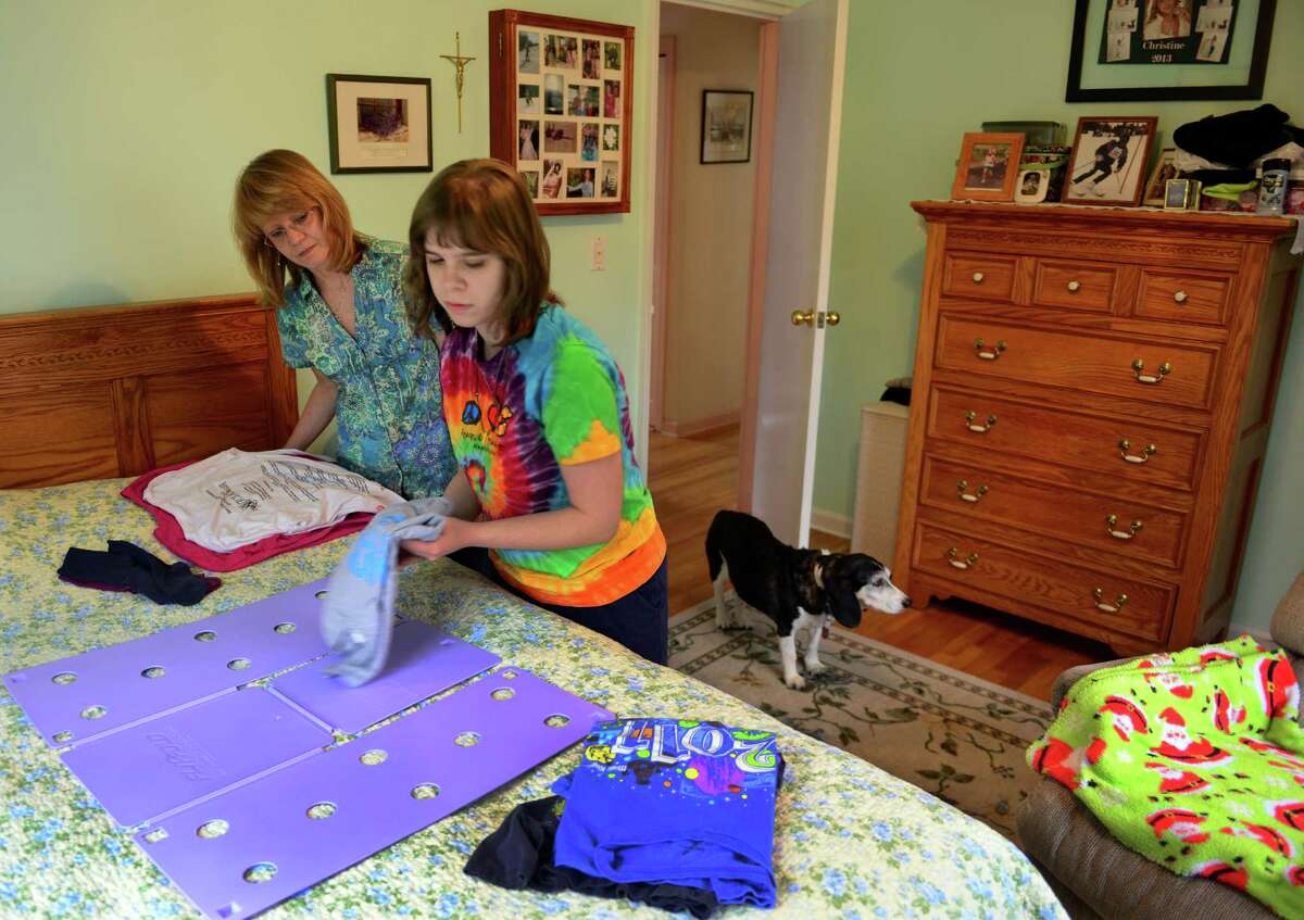 Michelle Rivelli looks on as her daughter Jessica Zangrillo folds her T-shirts at home in West Haven, Conn., on Wednesday Apr. 22, 2015. Zangrillo has autism and relies on services provided by the state. Proposed cuts in the state's budget might end the services the family uses to help her.