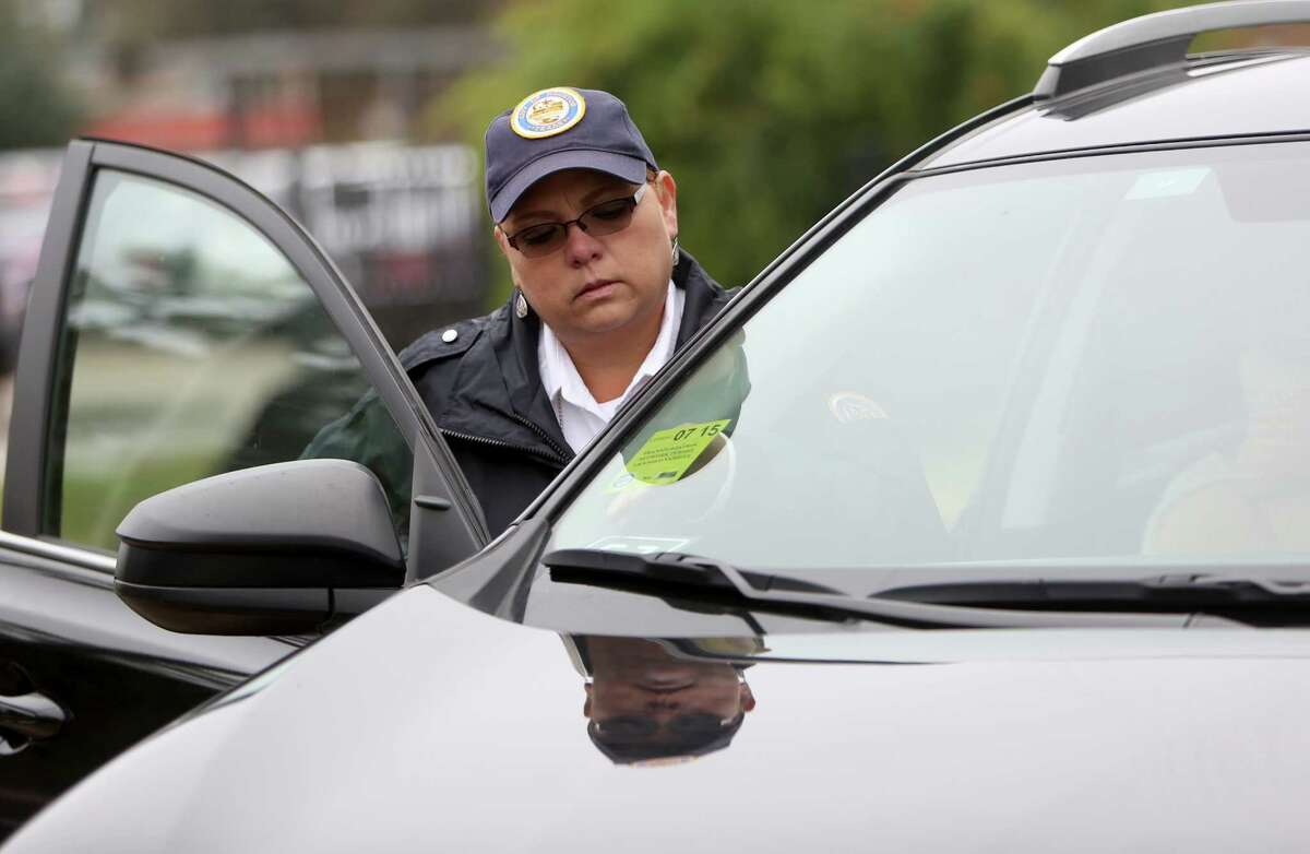 Irene Aguilar, a city of Houston regulatory investigator﻿, places a vehicle-for-hire permit on a company windshield last year. ﻿Drivers at that time also had their vehicles inspected for safety. ﻿