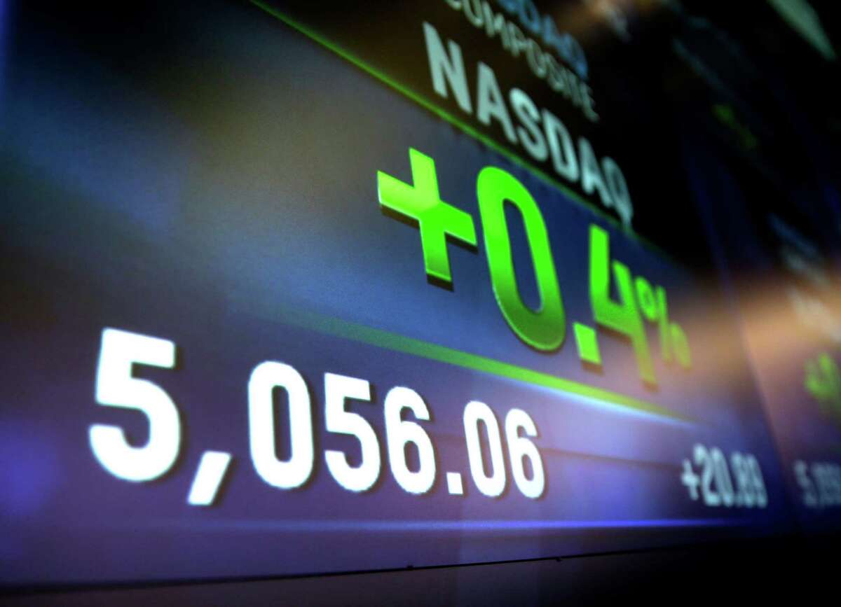 Market data is displayed Thursday on the screens at the Nasdaq MarketSite in New York. The Nasdaq composite has closed at a record high for the first time since the dot-com bubble of 2000.