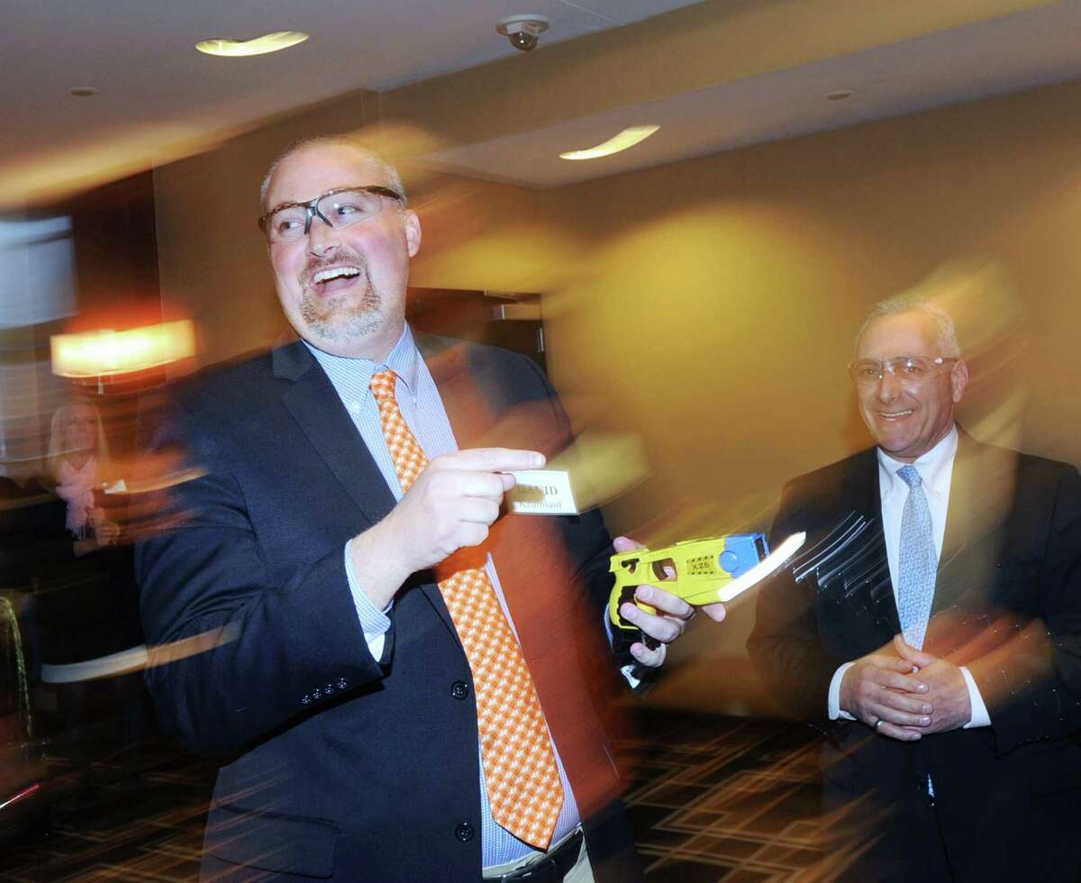 Greenwich resident David Krumlauf, left, laughs after firing a taser under the supervision of Greenwich Police Officer, Bob Ferretti, a firearms instructor with the department, during the Greenwich Citizens Police Academy Reunion Dinner at Hyatt Regency Greenwich, Thursday night, April 23, 2015. Krumlauf said he attended the academy in 2013 but did not get to fire a taser during his training then. According to the Chairman of the event, John Mastracchio, 160 people attended the dinner to raise funds and awareness for the academy that gives citizens a hands-on education in the complexity of law enforcement in the real world.