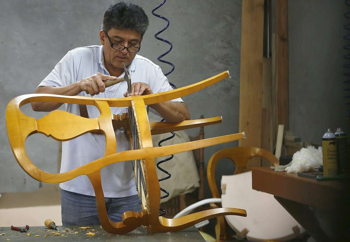 Upholsterer Angel Herrera works on a chair at Franciscan Interiors in San Francisco, California, on Wednesday, April 22, 2015.