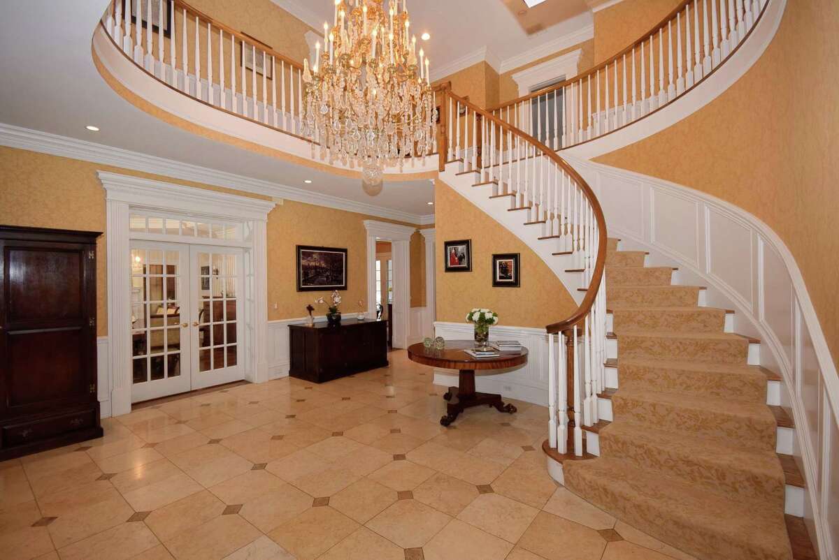 A marble foyer offers a grand entrance with a sweeping staircase and enough space to easily function as a gathering hall when entertaining guests.