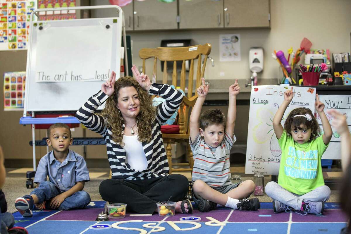 Pre-K teacher Vanessa de Simone Canseco participates in an active learning session with her students, from left, Braylon Nicholson, Ezequiel Portillo and Hailey Barrientos, at Marshall Elementary School on Friday. ﻿