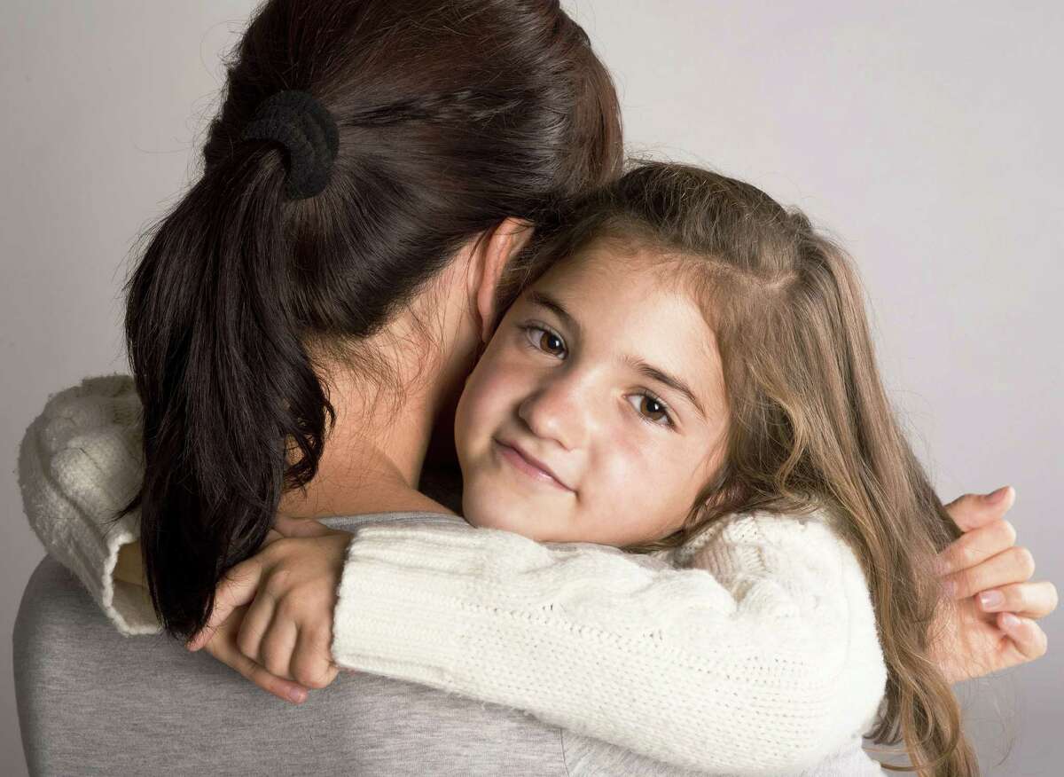 A mom gets a comforting hug from her daughter.