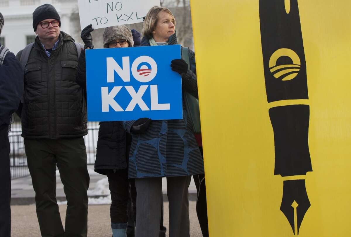 Melinda Pierce, center, with the Sierra Club, holds a "No KXL" sign, next to a large poster of a pen as she gathers with other opponents of Keystone XL oil pipeline to celebrate President Barack Obama's veto of the legislation outside the White House in Washington, Tuesday, Feb. 24, 2015, (AP Photo/Jacquelyn Martin)