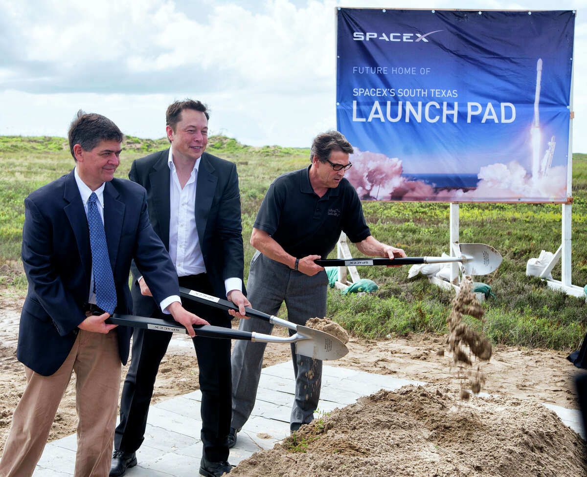 In a Sept. 22, 2014 file photo, U.S. Rep. Filemon Vela, left, SpaceX founder and CEO Elon Musk, center, and Texas Gov. Rick Perry turn the first shovel-full of sand at the groundbreaking ceremony for the SpaceX launch pad at Boca Chica Beach, Texas. The SpaceX venture, led by PayPal co-founder and electric car maker Musk, is one of two parts of the 21st-century space race being directed in the Texas by Internet billionaires.