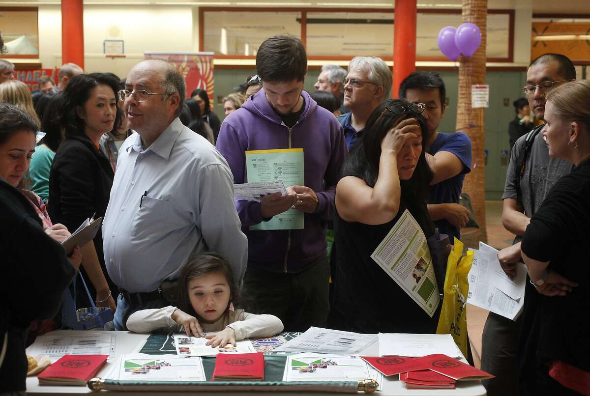 From left, Dina Bakour and Said Nuseiben talk with a representative of Alice Fong Yu Alternative School as Nuseiben's daughter Kindah Nuseibeh examines pamphlets while Brendan VanderMei, center, and Lily Tung Crystal, right, look over and discuss details at the SFUSD school enrollment fair at John O'Connell High School Oct. 25, 2014 in San Francisco, Calif.