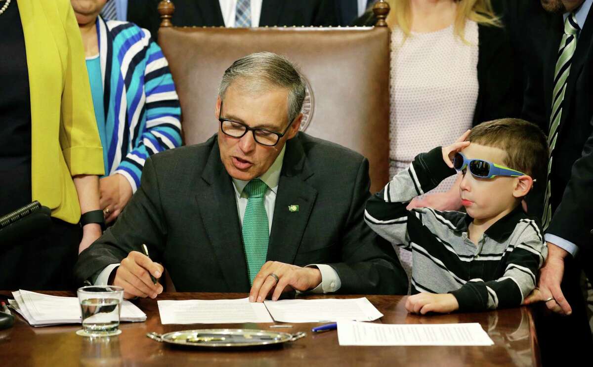 Haiden Day, 6, right, who has Dravet Syndrome, a form of epilepsy that his parents treat with medical marijuana, looks on as Washington Gov. Jay Inslee, left, signs a bill Friday, April 24, 2015 at the Capitol in Olympia, Wash., that overhauls Washington's medical marijuana market. Is it time for Texas to consider legalizing marijuana for legitimate medical uses?