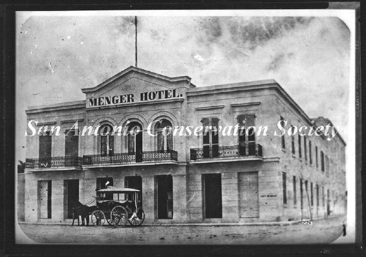 Copy print of an oblique view of the west and south facades of the original Menger Hotel. A horse drawn carriage stands in front of the Alamo Street entrance. Blum Street intersects to the south (at right).