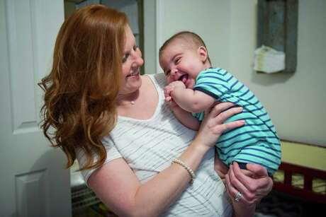 Lindsay Martin hugs her son Ridge after changing his diaper at the Martin's house in New Braunfels, Texas on Wednesday April 29, 2015. Lindsay and Clint Martin's two sons Case, 3, and Ridge, 6 months, both have Severe Combined Immunodeficiency or SCID, a disease that leaves them with a severely restricted immune system to combat infections and other ailments. When Case had problems breathing a few months after being born, the Martins scrambled to find a diagnosis. After Case was diagnosed with SCID (Lindsay Martin is a carrier) he underwent an umbilical cord blood transplant (the umbical cord was not his own, but from an individual in an anonymous pool of donors) and began to recover. Now he undergoes testing every year to determine if his health continues. Now the Martins are repeating the process with their second son, Ridge. They just returned to their home in New Braunfels after spending two months taking Ridge in and out of Texas Children's Hospital in Houston. "If not for people donating [umbilical} blood he would have died," Clint said, "[We're] thankful science and technology are where they are."