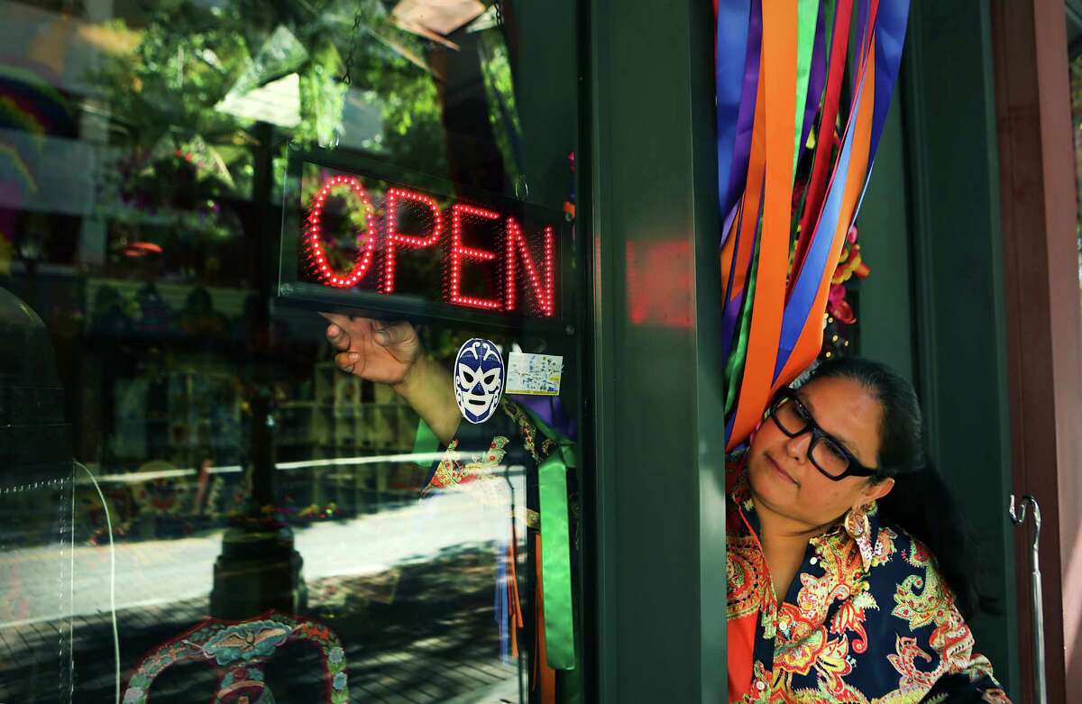 Veronica Sandoval, co-owner of Tienda La Garza at the corner of Houston and Lasoya, opens up her shop on Friday, May 1, 2015, turning on the open sign in the front window.