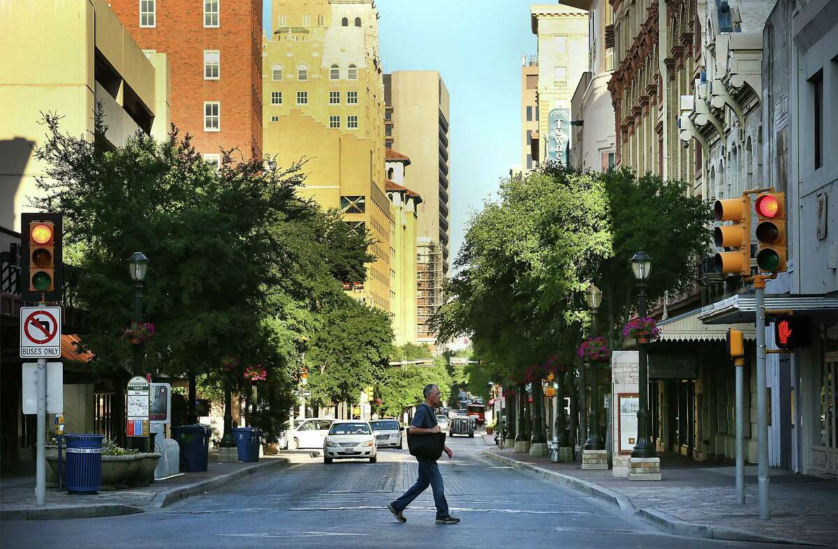 A man walks across Houston St. at Alamo St., as the early morning sun warms the city. The historic Houston St. may be experiencing some significant changes that could truly revive downtown.