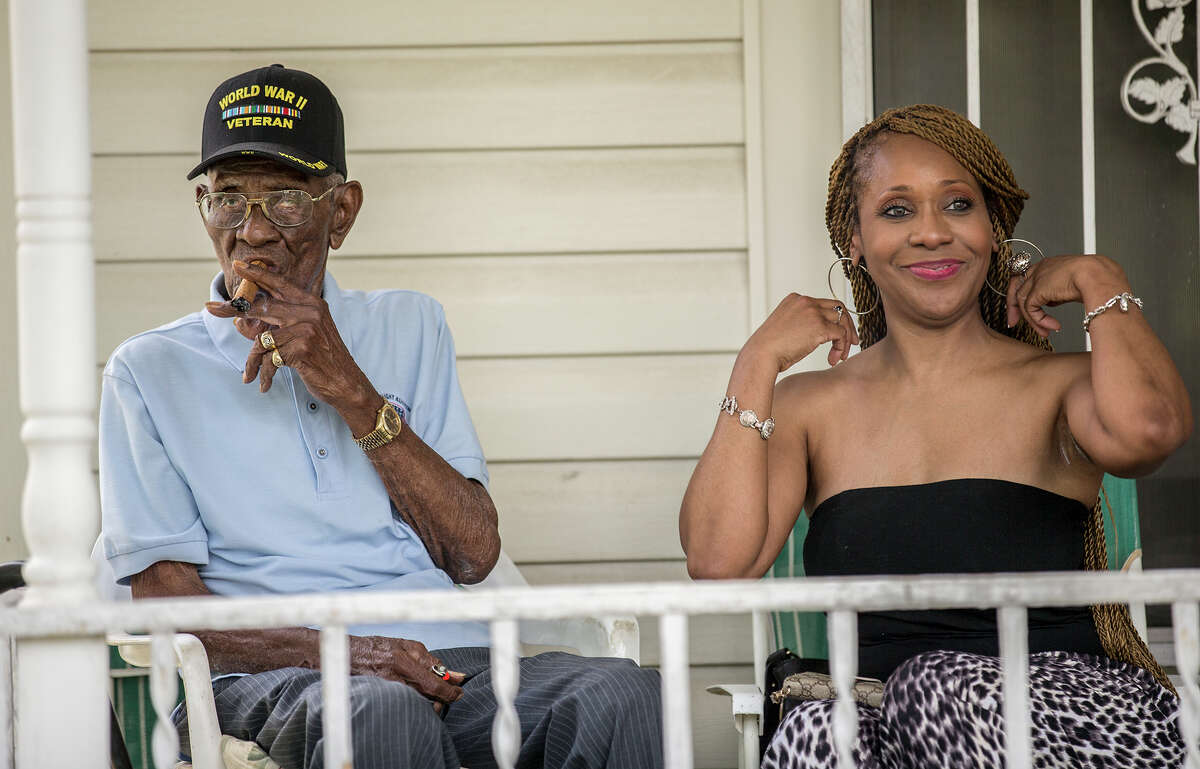 Richard Overton, left, smokes a cigar with friend Donna Shorts. Overton is considered to be the oldest living World War II veteran in the United States celebrated his 109th birthday on a front porch in East Austin, Texas, on Sunday, May 3, 2015, with friends and family. (Ricardo B. Brazziell/Austin American-Statesman via AP)
