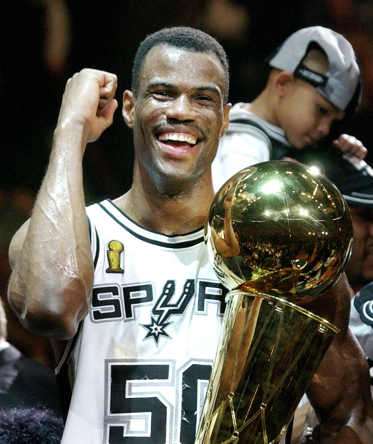 In this June 15, 2003 file photo, center David Robinson holds the NBA championship trophy after the Spurs beat the New Jersey Nets 88-77 in Game 6 of the NBA Finals in San Antonio.