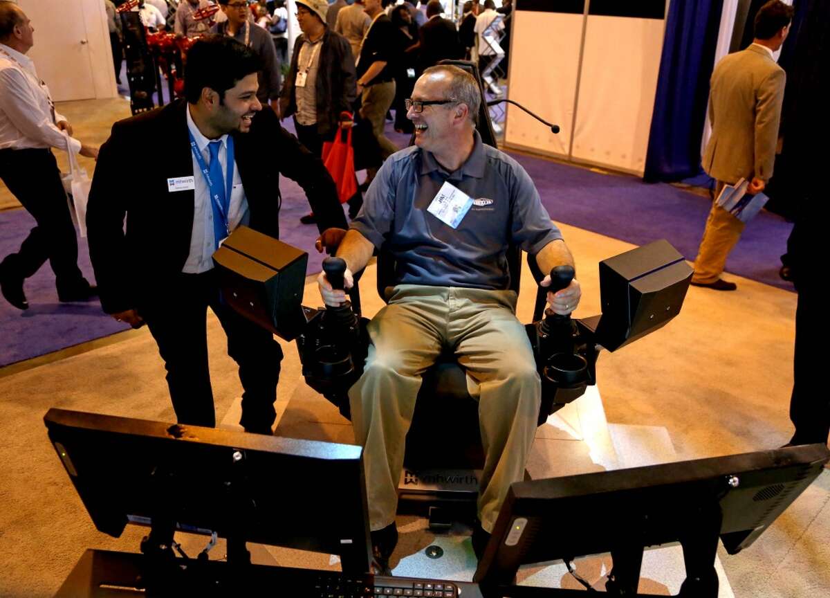 Manas Goyal, left, of MHWirth, Houston, shows Jim Shifrin, of Dixon Valve & Coupling Company, Houston, how to simulate making up pipe on a third generation operator chair at the Offshore Technology Conference at the NRG Center Monday, May 4, 2015, in Houston, Texas. ( Gary Coronado / Houston Chronicle )