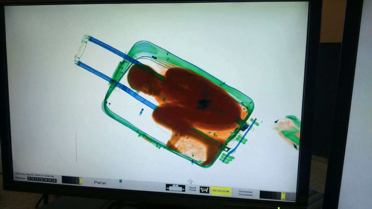 In this photo released by the Spanish Guardia Civil on Friday, May 8, 2015, a boy curled up inside a suitcase is seen on the display of a scanner at the border crossing in Ceuta, a Spanish city enclave in North Africa. A Spanish court has ordered the detention of a father who allegedly hid his 8-year-old son inside a closed suitcase in an attempt to smuggle the child illegally into Europe. A police statement said guards stopped a 19-year-old Moroccan woman who looked nervous as she waited in line Thursday at the land border crossing in Ceuta