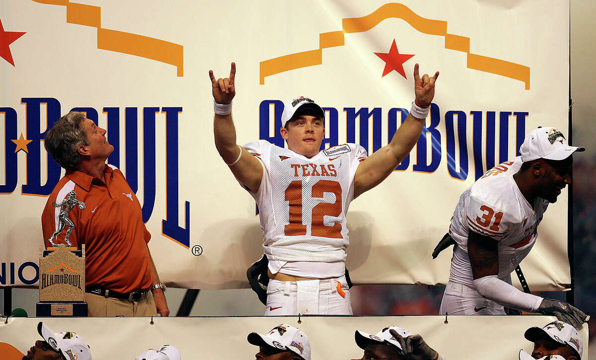 Longhorns’ Colt McCoy (center) gestures the “Hook ’em Horns” sign before he receives the offensive player of the game as head coach Mac Brown (left) and defensive player of the game Aaron Ross (right) join McCoy on stage after defeating the Iowa Hawkeyes 26-24 to win the 2006 Alamo Bowl at the Alamodome on Dec. 30, 2006.
