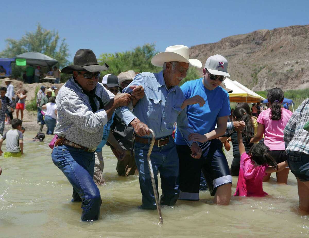 An elderly man is helped across the Rio Grande from Mexico to Texas during the Voices From Both Sides festival held at Lajitas, Texas, on Saturday, May 9, 2015. Many people from Mexico and the United States gathered and in some cases reunited with family members that they have not seen for years because of the border.