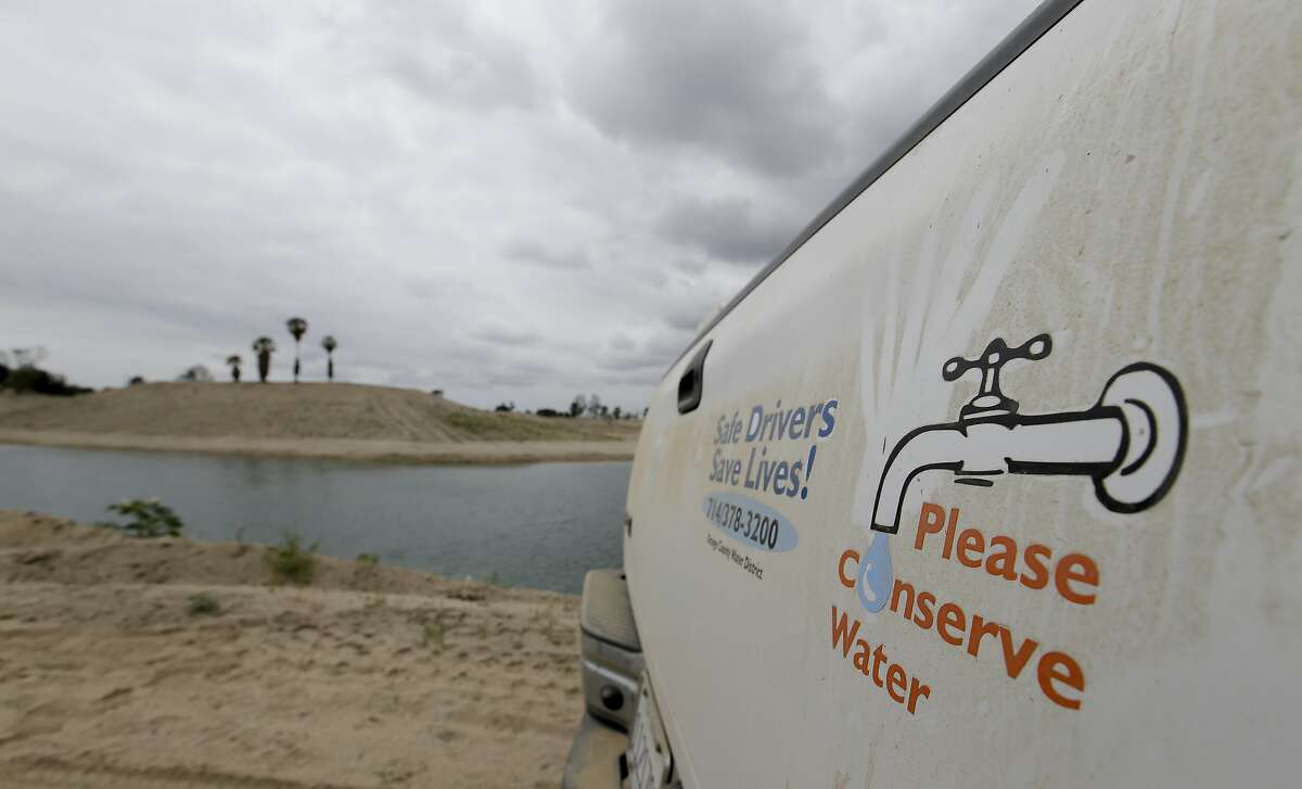 In this May 6, 2016 file photo, a sign urges water conservation in front of recycled wastewater in a holding pond used to recharge an underground aquifer at the Orange County Water District recharge facility in Anaheim, Calif. The water district, which serves 2.4 million people near Los Angeles, wants credit for sending wastewater through ground basins for drinking, as they face statewide cuts to urban water use approved this month. (AP Photo/Chris Carlson)