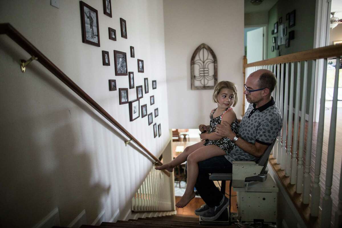 ﻿Jay Smith and his daughter, Peyton, ride a stair lift at their home in Austin﻿ last week. Smith said he fears a right-to-try law won't help ALS patients because the FDA's fast-track drug program doesn't.﻿